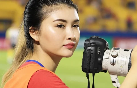 Nguyệt Hà cầm máy ảnh bên sân bóng